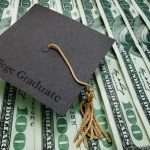 college graduate cap on assorted hundred dollar bills